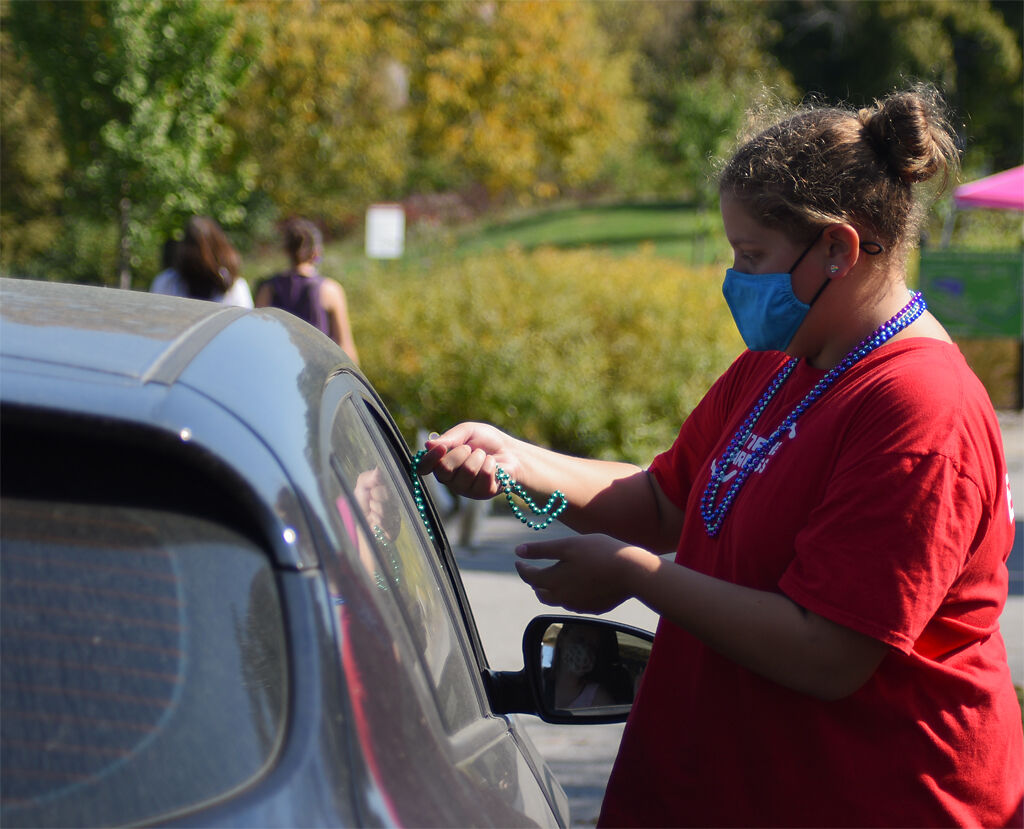 Kaylee McCubbin hands green beads and sand to a passerby